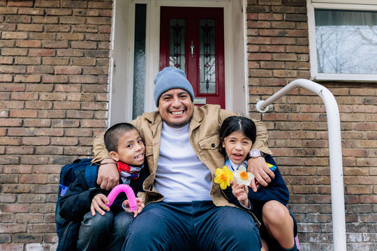 Father sitting with children smiling on brick porch