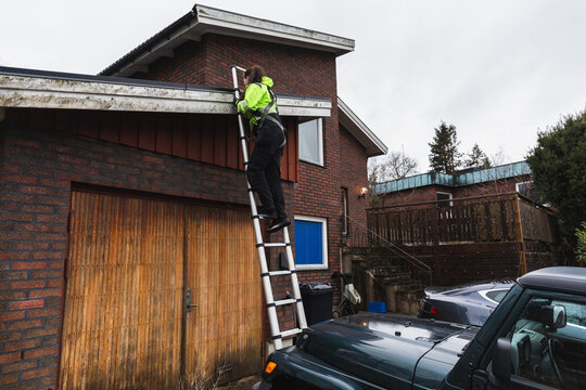 Technician Working on Ladder for Solar Roof Check
