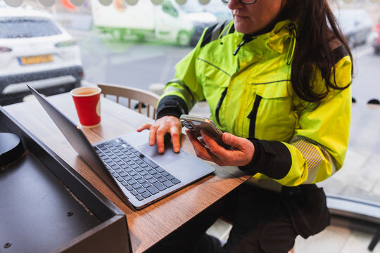 Female Technician Using Phone and Laptop During Break