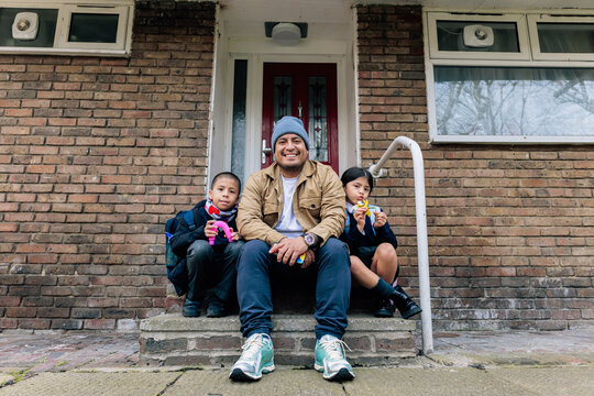 Father sitting with children smiling on brick porch