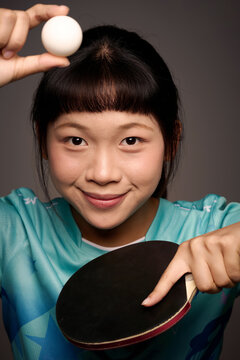 Chinese woman in sportswear is holding a ping-pong paddle and ball