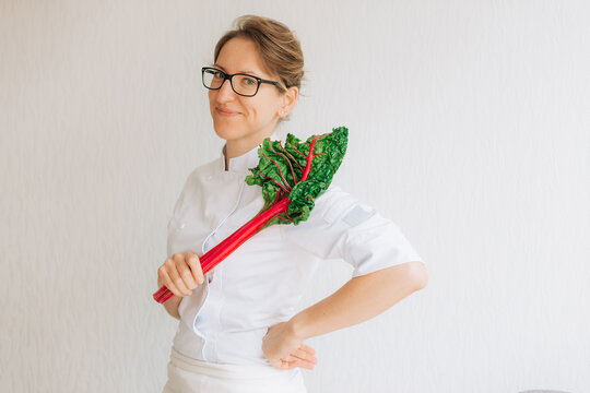 Female chef holding fresh chard leaf on white background