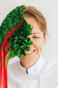 Portrait of laughing female chef with chard leaf