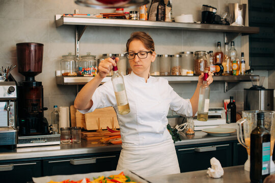 Female chef inspecting bottles in professional kitchen