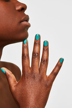 Woman's hand with turquoise manicure touching chin