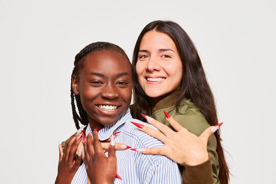 Diverse women embracing with colorful long nail art