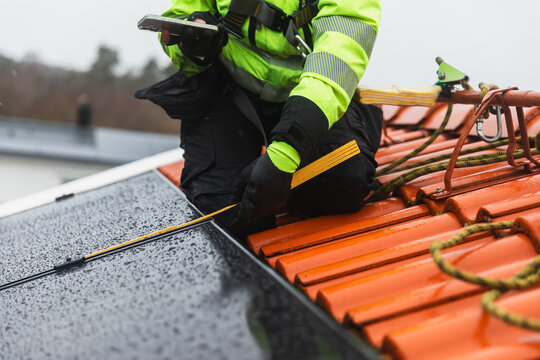 Solar Technician Measuring Distance of Panel Connection on Roof