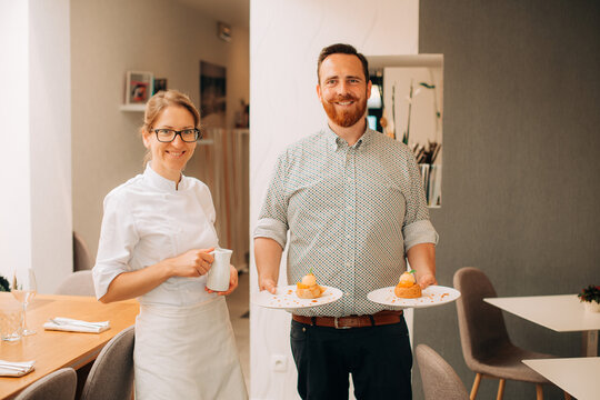 Chef and waiter presenting gourmet desserts in restaurant