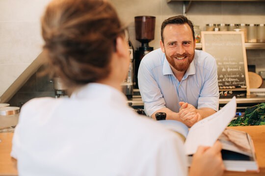 Chef and a customer with a book in open kitchen restaurant