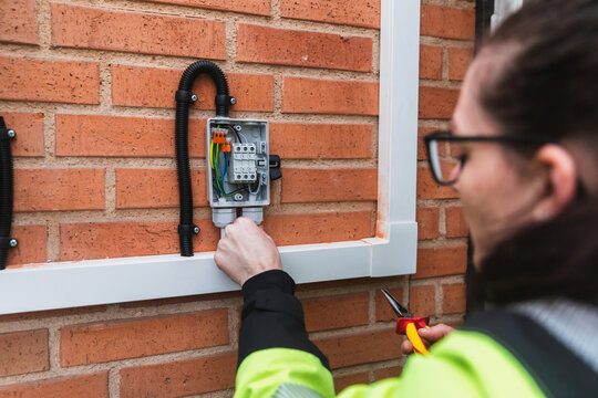 Specialist Inspecting Electrical Junction Box on Brick Wall