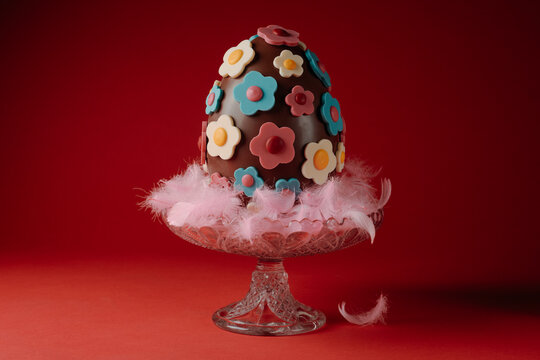 a decorated chocolate easter egg on a glass cake stand