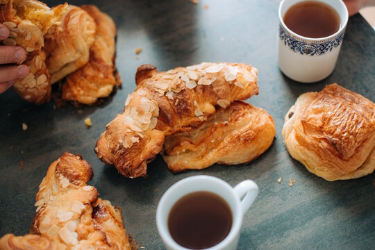 Fresh croissants and pastries with tea on kitchen table