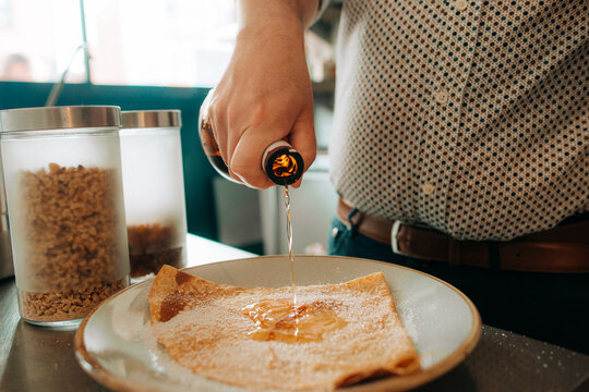 Pouring syrup over crepe dessert close-up