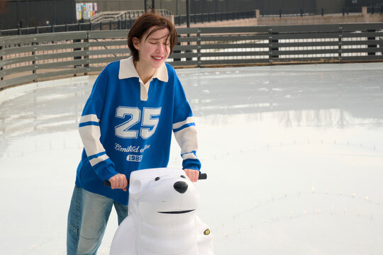 Woman skating on ice rink with the help from a polar bear