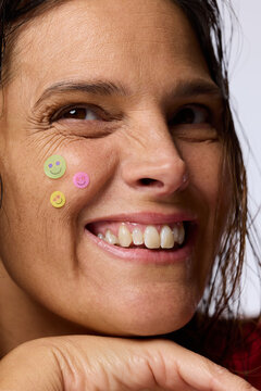 Woman Smiles With Stickers on Face in Studio Setting