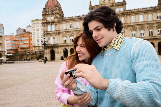 Couple reviewing photos on camera in historic city square