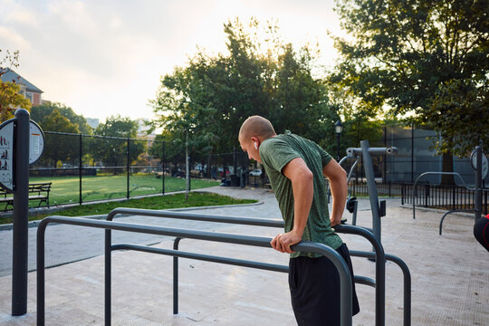 Individual works out on parallel bars in an outdoor gym.