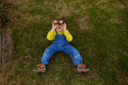 Boy lying on grass looking through binoculars