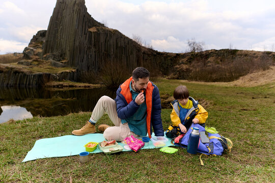Father and son having picnic near basalt rocks