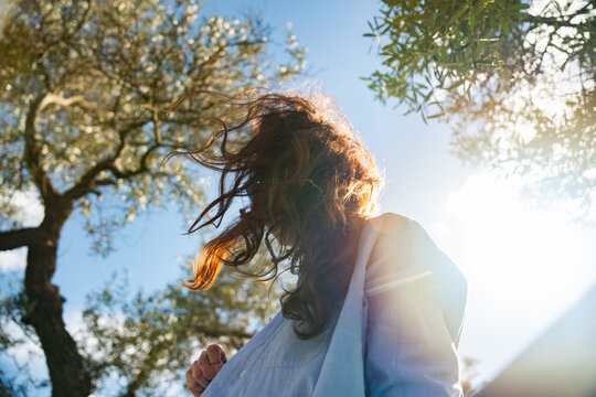 Woman with Wind Blown Hair Standing in Sunny Nature