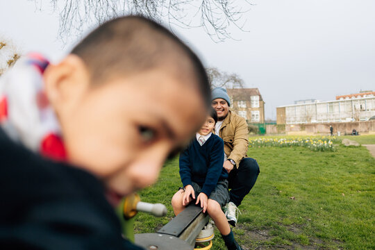 Father picking up children from school playing in park