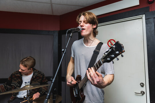 Young Male Musician Singing and Playing Electric Guitar in Studio