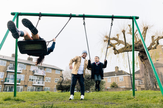 Father playing with children at a swing set