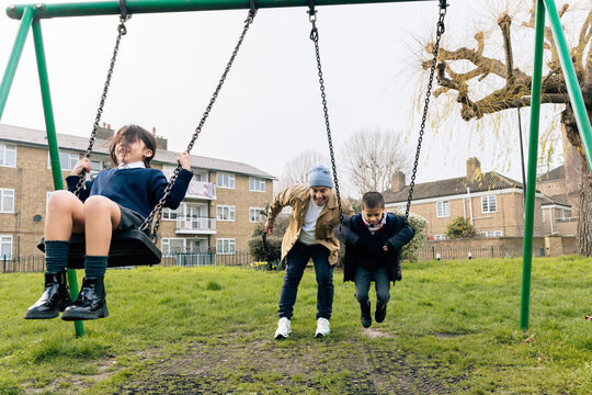 Father and children playing on swings after school
