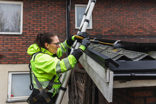Technician Using Measuring Tape for Rooftop Solar System Inspection