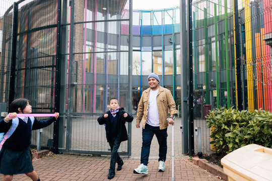 Man picking up children from school using crutch