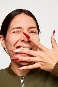 Woman winking, showing playful red manicure and nail art