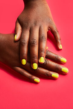 Well-groomed hands crossing with vibrant yellow nails