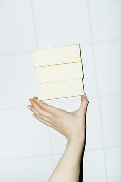 Hand holding yellow mockup packages with space for text or design 