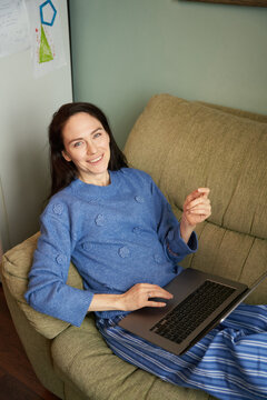 Woman using laptop and looking at camera