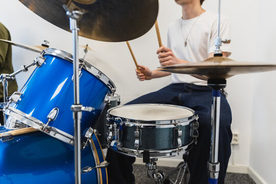 Young Drummer Playing Blue Drum Set in Music Studio
