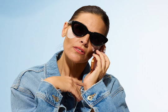Woman Using Phone While Wearing Sunglasses and Skincare Mask