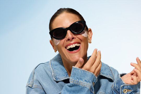 Woman Applies Skin Care in Sunny Outdoor Setting With Sunglasses