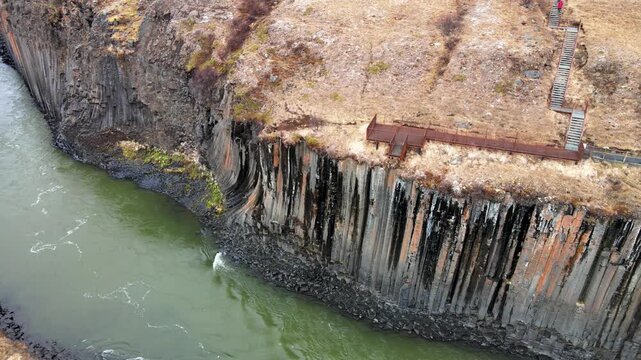 Aerial view of Studlagil Canyon featuring unique basalt column formations and a viewing platform above the river in Eiriksstadhir, Mulathing, Iceland.