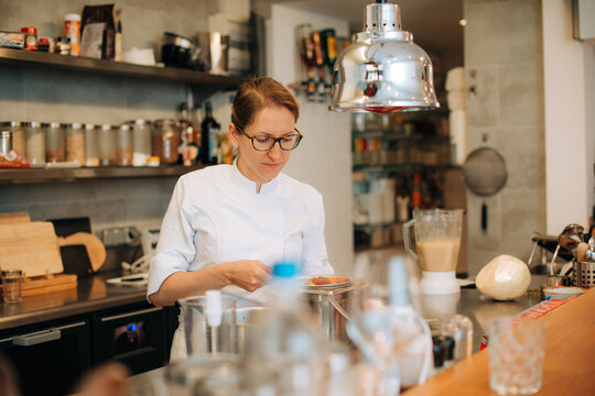 Female chef preparing food in modern professional kitchen
