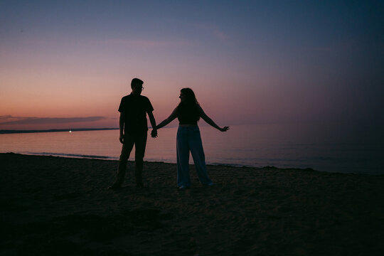 silhouettes portrait of young couple walking at sunset