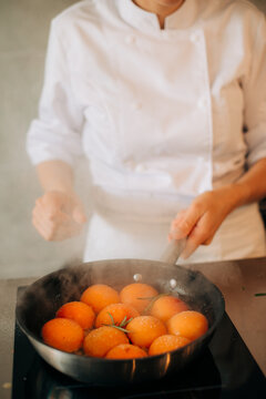 Chef caramelizing apricots in frying pan with sugar and herbs