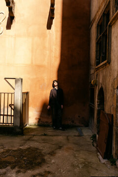 Young man leaning againts a terracotta wall in Lyon France. 