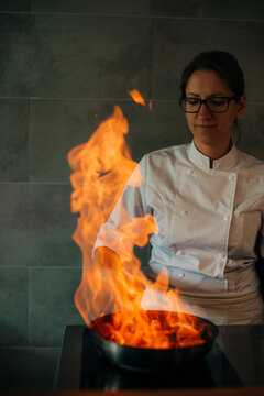 Chef cooking flambe dessert with flames in kitchen