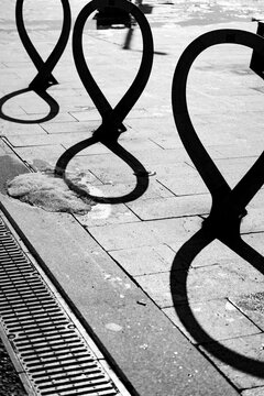 Shadows of bike racks on a sunny street in an urban setting