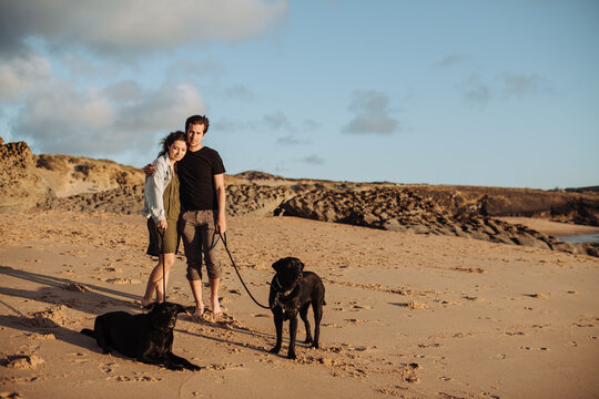 Couple Standing with Dogs on Sunny Beach