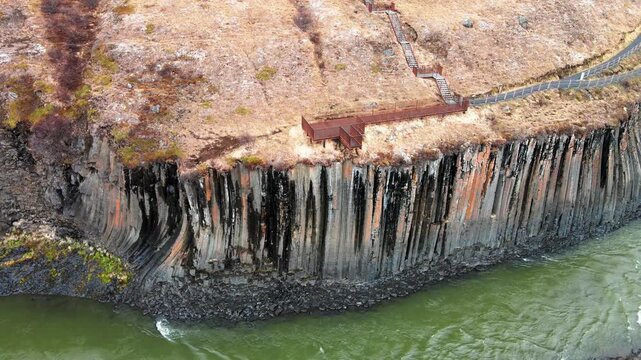 Aerial view of Studlagil Canyon featuring towering basalt columns and the Jokulsa a Bru river with a wooden viewing platform in Eiriksstadhir, Mulathing, Iceland.