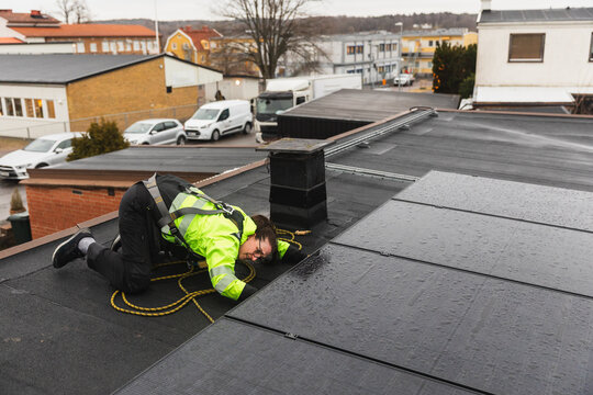 Specialist Checking Electrical Connections Under Solar Panels