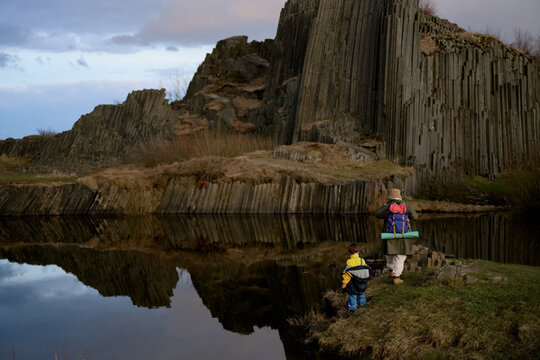 Mother and child exploring basalt lake landscape