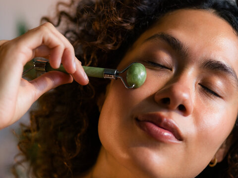 Woman massaging her face using jade roller 