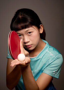 Chinese woman in sportswear is holding a ping-pong paddle and ball